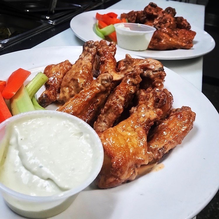 A plate of chicken wings with ranch and vegetables.