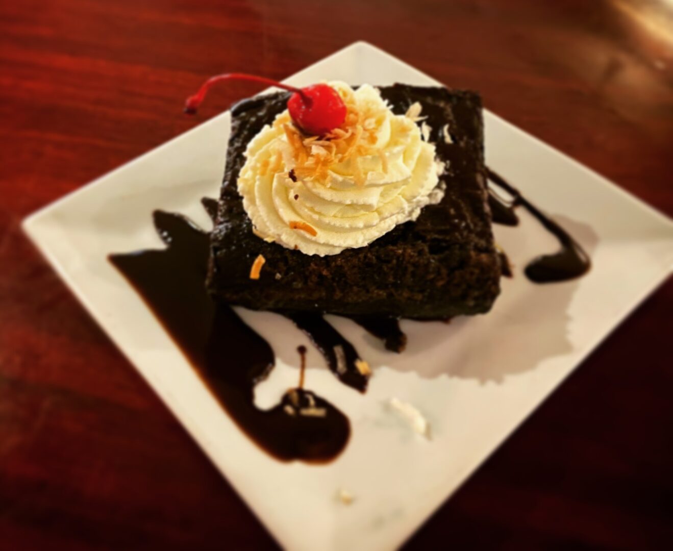 A piece of chocolate cake with whipped cream and cherries on top.